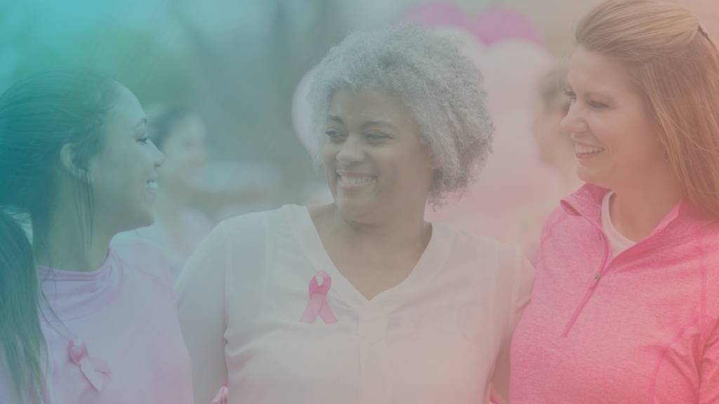 Mulheres sorriem e usam fita rosa em apoio ao Mês de Conscientização sobre o Câncer de Mama.