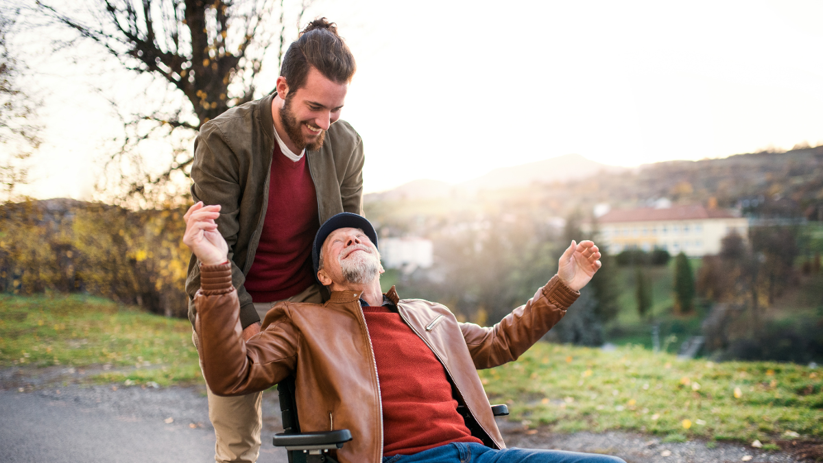 Young man pushing older man in wheelchair