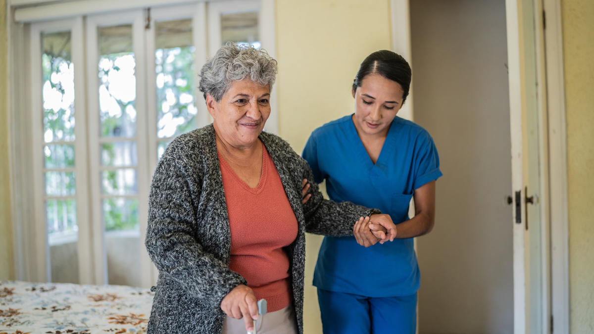 Nurse helping older woman walk.