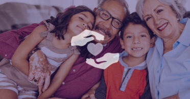 Pareja de ancianos se abraza y sonríe con sus nietos en la sala de estar.