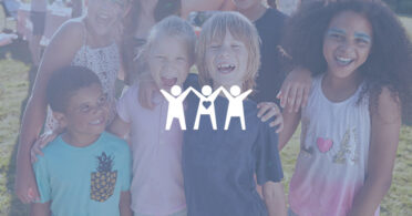 Diverse group of children gathered together and smiling at outdoor event.