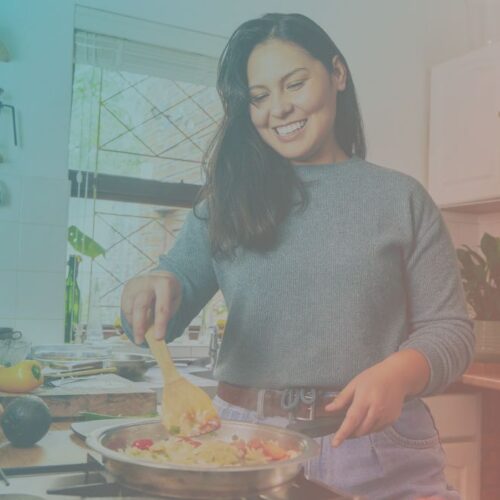 Una mujer sonríe mientras cocina en su cocina.